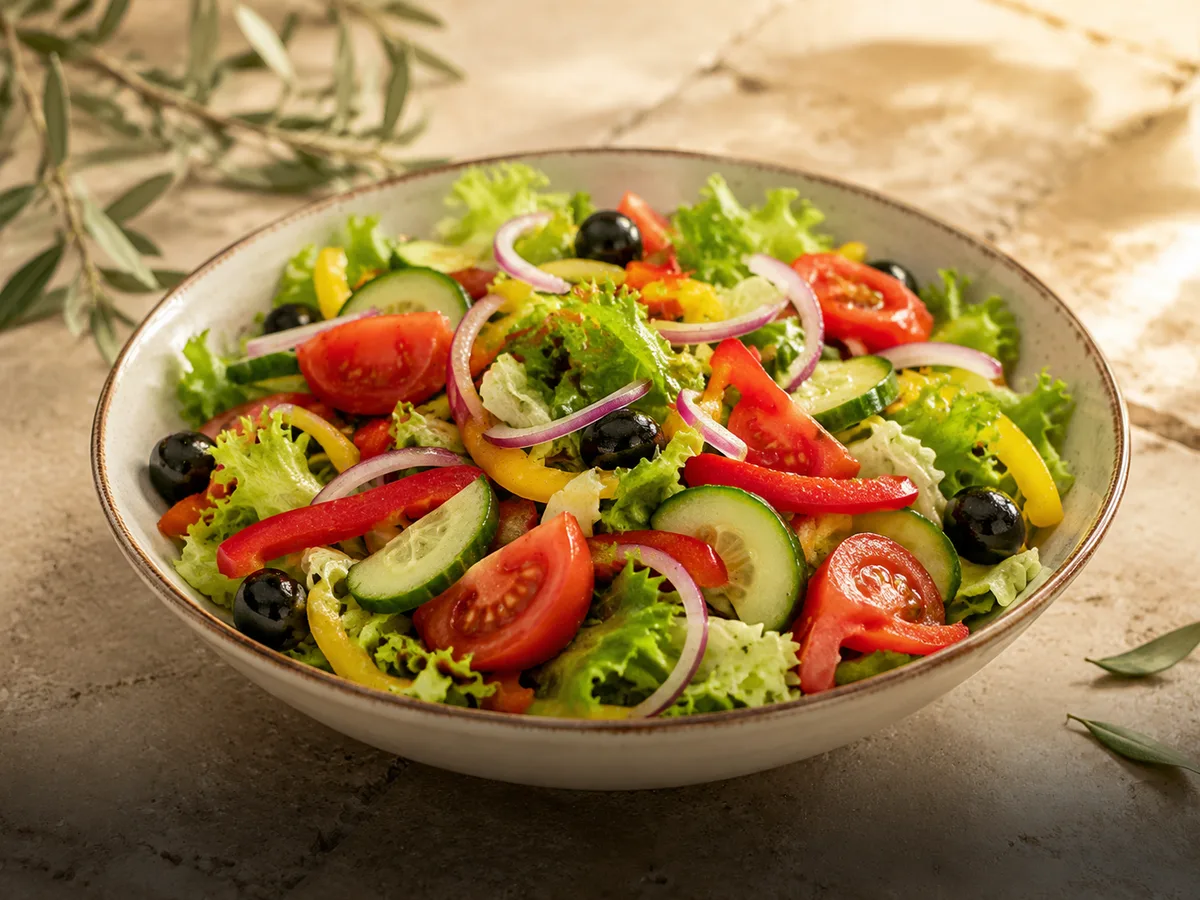 Imagine ilustrativă cu un bol de salată asortată cu roșii, castraveți, ardei și măsline